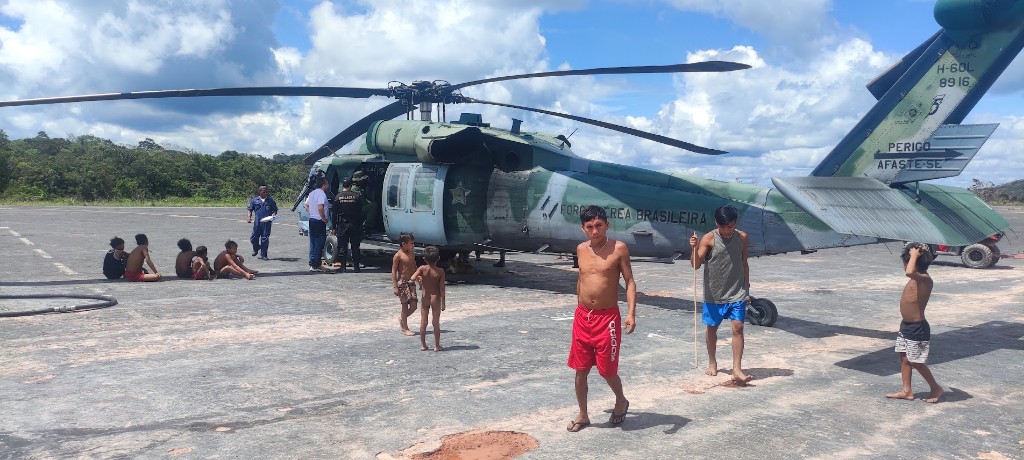 Helicóptero H-60 da Força Aérea em pista na Amazônia, com moradores da aldeia ao redor